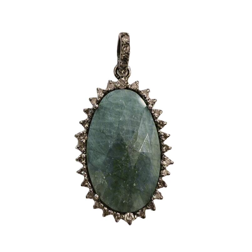 Pendant with green stone and silver frame on a textured beige background