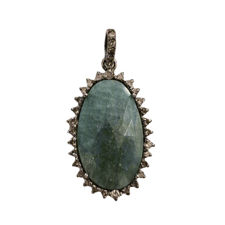 Pendant with green stone and silver frame on a textured beige background