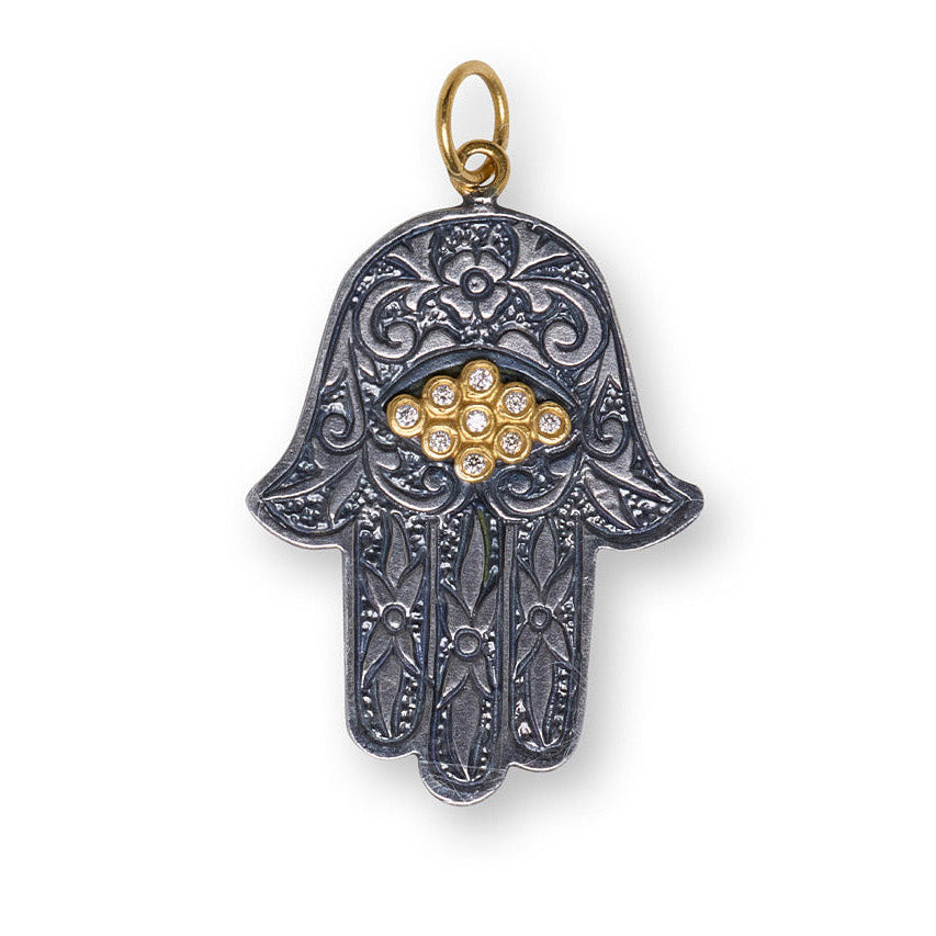 Decorative pendant shaped like a hand with intricate patterns on a white background