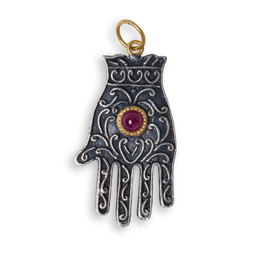 Decorative hand-shaped pendant with a red gemstone on a white background