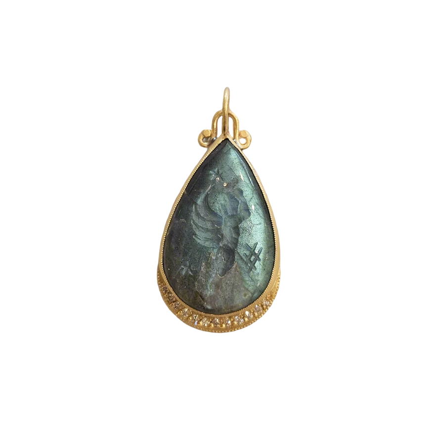 Teardrop-shaped pendant with gold frame and green stone on beige fabric background