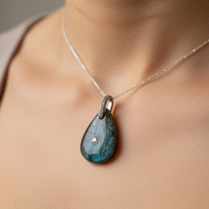 Teardrop-shaped pendant with a textured surface on a beige fabric background