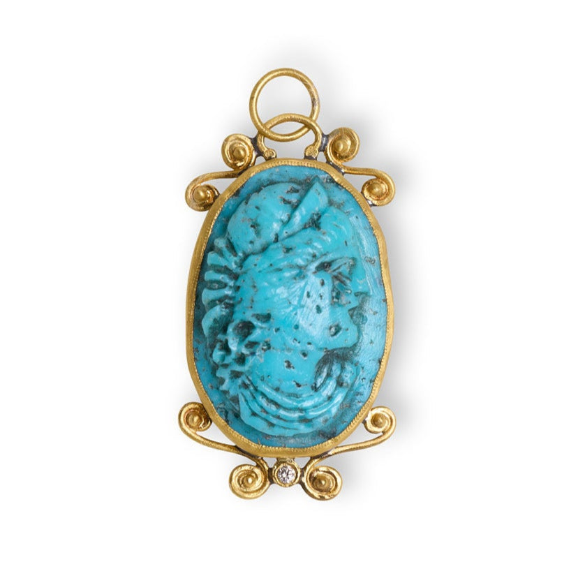 Gold pendant with a blue stone on a white background
