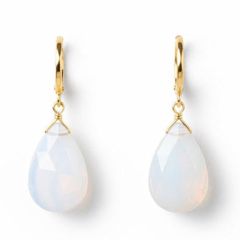 Close-up of a person wearing a light blue teardrop earring with gold accents.