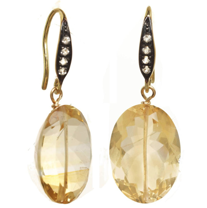 Gold earrings with large yellow gemstones on a white background