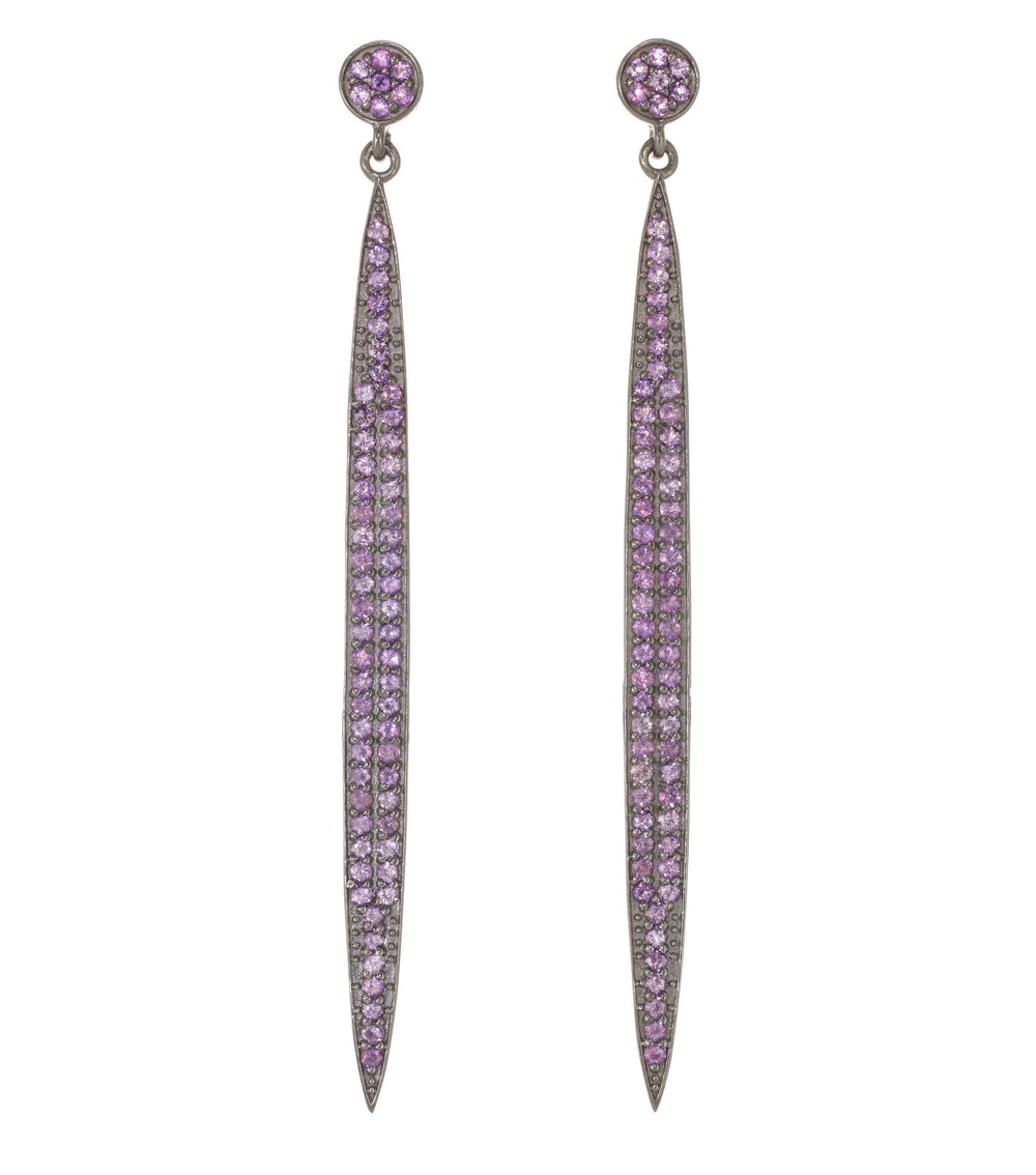 Pair of long, thin earrings with purple gemstones on a white background
