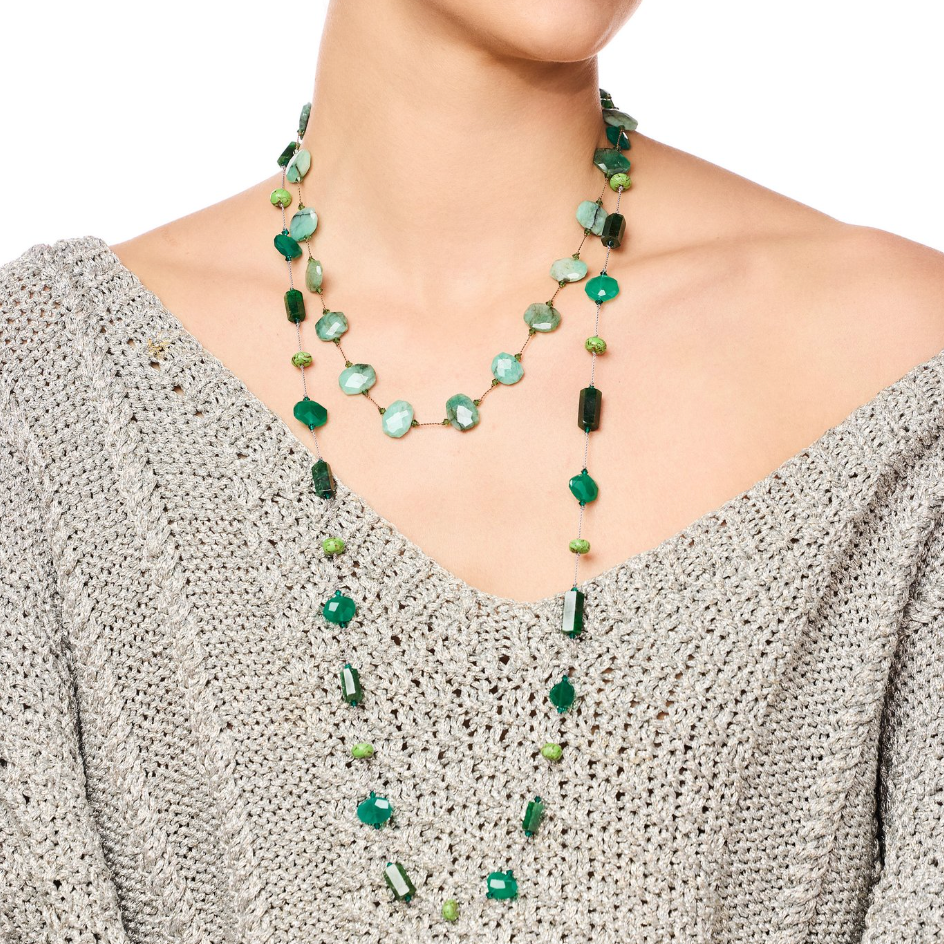 Woman wearing a green beaded necklace against a white background
